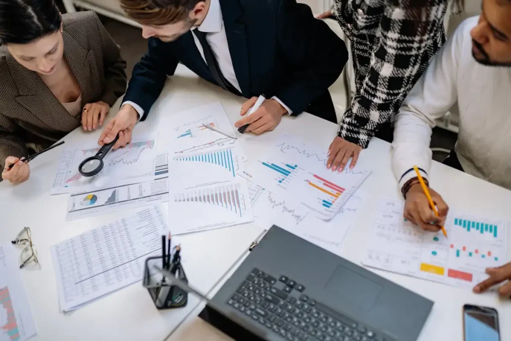 Tim profesional sedang menganalisis grafik dan data keuangan dalam rapat strategis