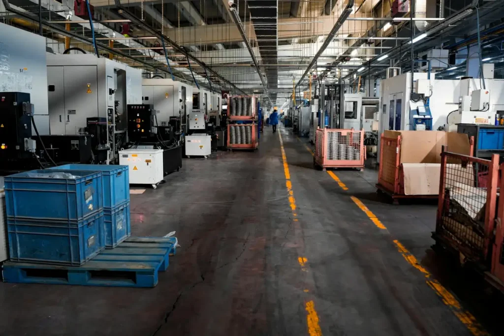 Lantai produksi pabrik industri dengan mesin dan area kerja yang menganggur